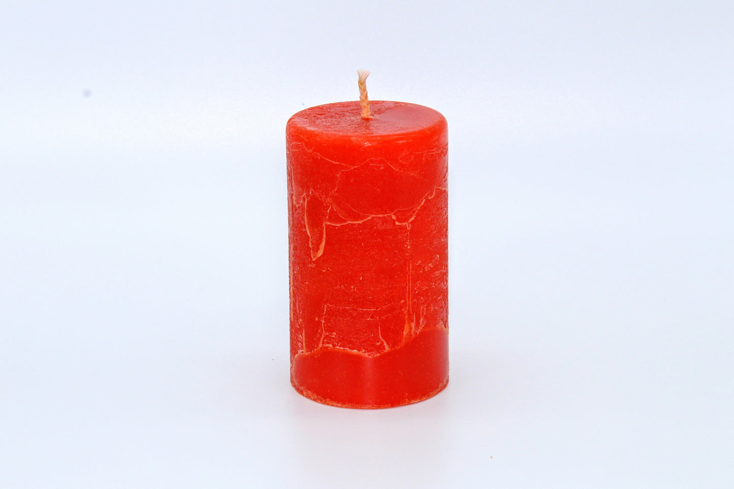 Orangefarbene zylindrische Kerze mit rohem Effekt